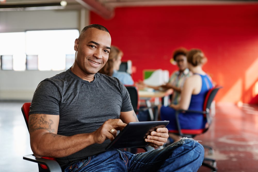 Confident male designer working on a digital tablet in red creative office space Confident male designer working on a digital tablet in red creative office space